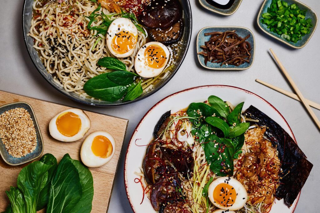 Zwei Teller Ramen mit unterschiedlichen Beilagen, darunter Ei, Wakame und Fleisch